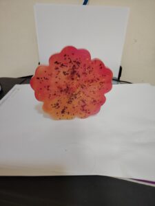 Handmade resin coaster in a red-orange flower shape with glitter accents
