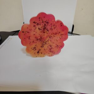 Handmade resin coaster in a red-orange flower shape with glitter accents