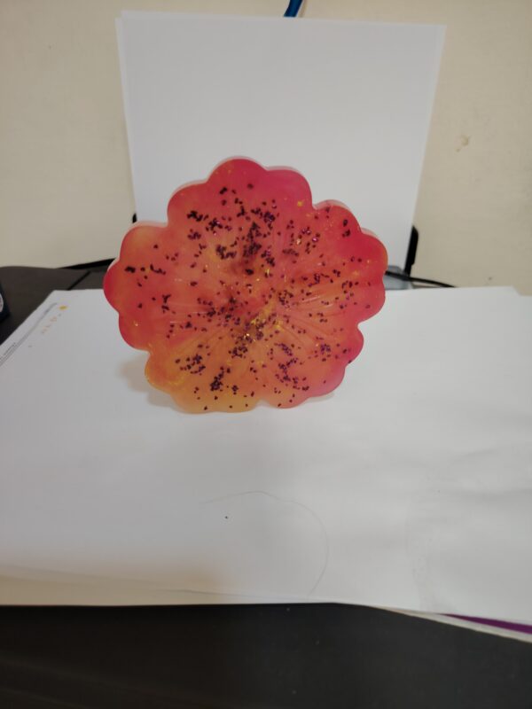 Handmade resin coaster in a red-orange flower shape with glitter accents